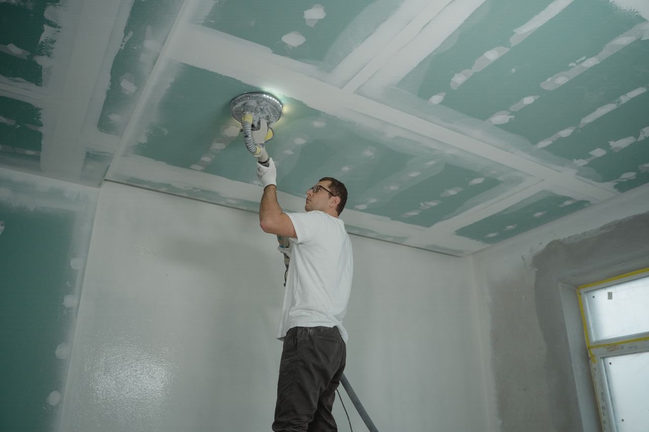 Home A worker expertly polishes a ceiling indoors, demonstrating home renovation skills.